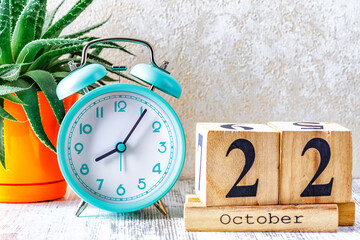 Wooden calendar with the date October 22.Monthly calendar for planning and management concept with alarm clock on wooden background