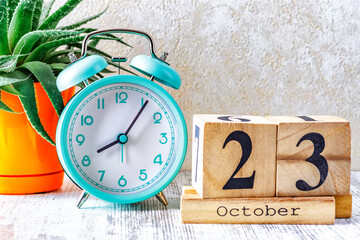 Wooden calendar with the date October 23.Monthly calendar for planning and management concept with alarm clock on wooden background