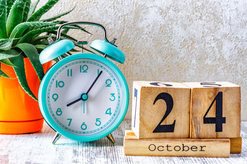 Wooden calendar with the date October 24.Monthly calendar for planning and management concept with alarm clock on wooden background