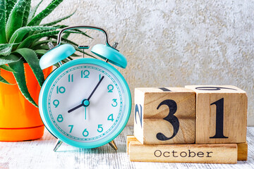 Wooden calendar with the date October 31.Monthly calendar for planning and management concept with alarm clock on wooden background
