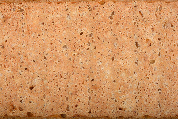 A close-up shot of the lower part of homemade bread reveals its porous texture and a golden-brown hue.
