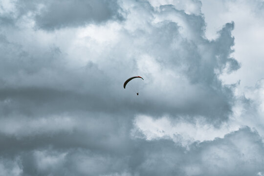 View of a paraglider soaring against a backdrop of dramatic, textured storm clouds in Ortisei, Trentino-Alto Adige, Italy.