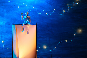 Halloween Books.Skeleton Puppet Reading Book at Night.Skeleton on Book with Halloween Lights.