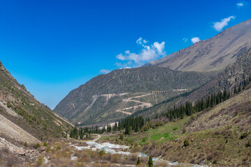 Ala-Archa Park, Mountainous terrain featuring a winding path, flowing river, pine trees, steep slopes, inviting setting for trekking, hiking, mountaineering, adventure, and nature exploration