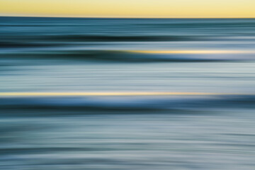 Soft, flowing ocean waves captured in a blur during sunset.