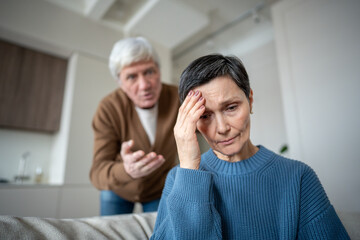 Senior upset despair woman with head in ahnds enduring verbal aggression and accusation from unstable partner in dysfunctional relationship. Psychological control, silent suffering, abuse manipulation