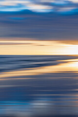 Abstract motion blur capturing the ocean and sky at sunset.