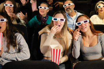Audience wearing 3d glasses enjoying film and eating popcorn in movie theater