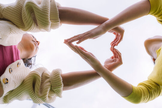 Women making heart shape gesture outdoors showing friendship