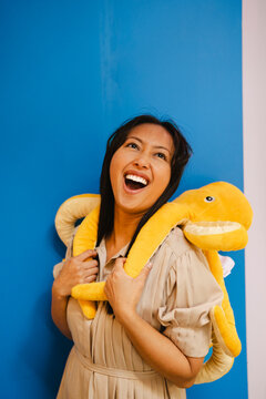 Happy woman posing with plush octopus against blue background