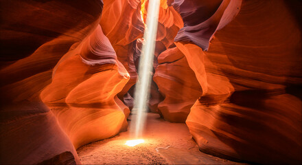 Light beams shine through the narrow crevices of Antelope Canyon illuminating the stunning rock formations