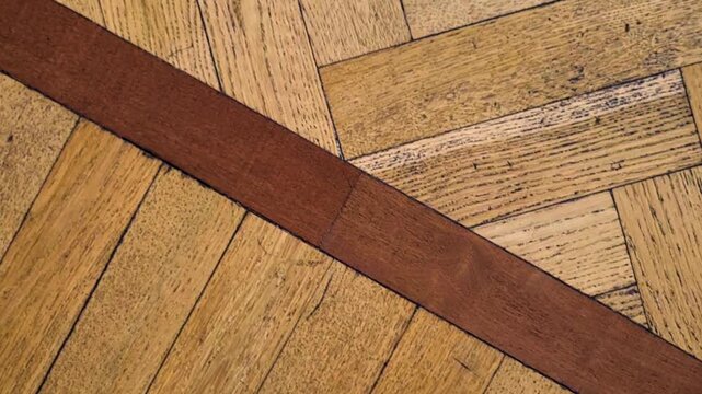 Diagonal parquet flooring with dark brown wood inlay. Dolly move, top view.