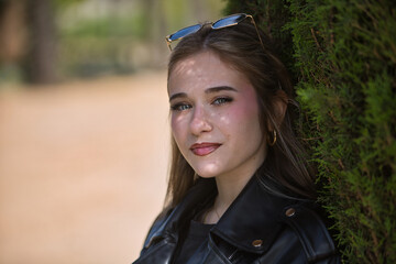 Portrait of young woman, beautiful, blonde, green eyes, with leather jacket and sunglasses, looking...