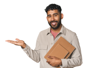 Hispanic student holding notebooks in studio showing a copy space on a palm and holding another hand on waist.