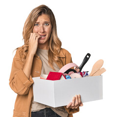 Young Caucasian blonde moving with a box biting fingernails, nervous and very anxious.