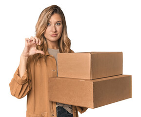 Blonde Caucasian moving with large boxes showing a dislike gesture, thumbs down. Disagreement...