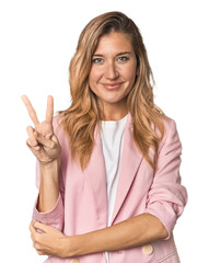 Young blonde in stylish pink suit showing number two with fingers.
