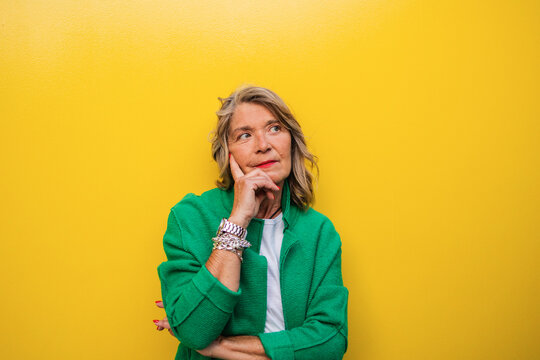 Thoughtful tourist in green jacket in front of yellow wall in Madrid