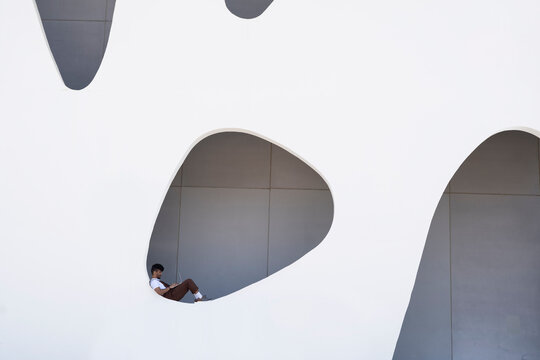 Young man working on laptop with hole in building