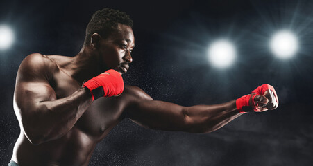 Professional african man with red boxing wraps on fighting on boxing arena, stadium lights...