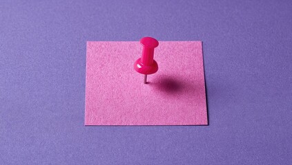 Pink pushpin in a square of pink sticky note on a purple background