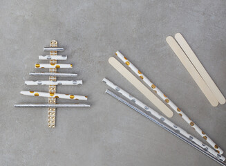 sparkly straw Christmas tree with some straws and popsicle sticks on grey.