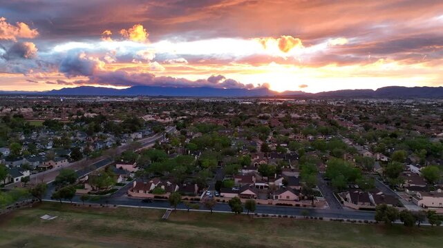 Aerial view of the city landscape under a dramatic sunset sky, with contrasting orange and purple hues over the horizon, Chandler, Arizona, United States.