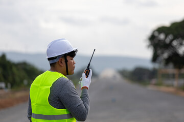 A engineer   on a vast road construction site. Traffic cones and barriers are, signifying   area ...