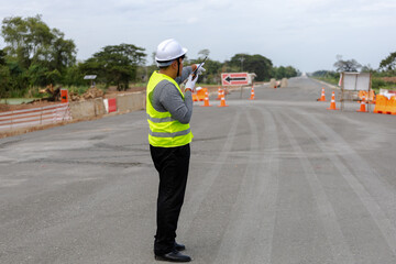 A engineer   on a vast road construction site. Traffic cones and barriers are, signifying   area ...
