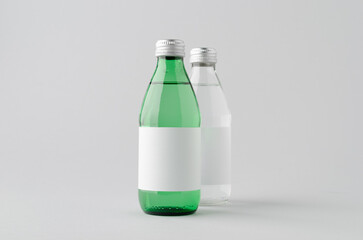 Clear and green glass water bottle mockup with blank label on neutral background