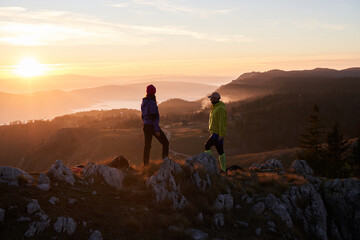 A joyful couple celebrates their victorious ascent to the mountain summit, embracing each other...