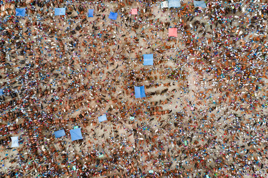 Aerial view of a densely packed crowd, with a mosaic of brown tones punctuated by vibrant blue and pink canopies, Mahasthan, Rajshahi Division, Bangladesh.