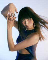 Elegant Asian female model in dynamic pose with jewelry.