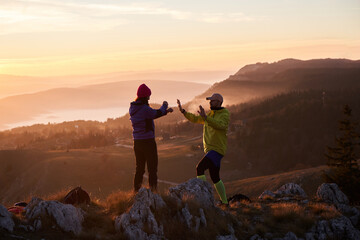 A joyful couple celebrates their victorious ascent to the mountain summit, embracing each other...