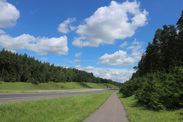 Scenic asphalt road stretching into the horizon in peaceful Belarusian countryside, summer landscape with blue sky, travel and freedom concept