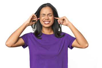 Young Latina posing in studio covering ears with fingers, stressed and desperate by a loudly ambient.
