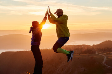 A joyful couple celebrates their victorious ascent to the mountain summit, embracing each other...