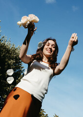Young woman throwing rose petals in the garden under blue sky