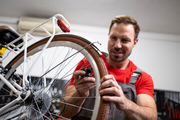 Professional bicycle serviceman checking spokes on the rear wheel.