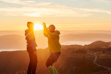 A joyful couple celebrates their victorious ascent to the mountain summit, embracing each other...