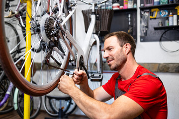 Professional bicycle serviceman replacing sprocket and gear chain inside workshop.