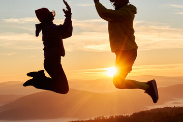 A joyful couple celebrates their victorious ascent to the mountain summit, embracing each other...