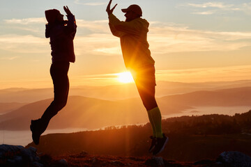 A joyful couple celebrates their victorious ascent to the mountain summit, embracing each other...