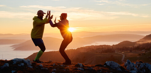 A joyful couple celebrates their victorious ascent to the mountain summit, embracing each other...