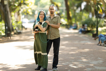 Couple walking cat on leash in park