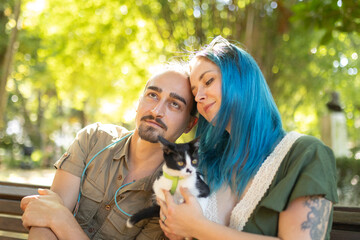 Young couple holding a kitten are enjoying a sunny day in the park
