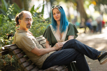 Young couple relaxing on bench in park with pet rat