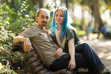 Young couple relaxing on bench in lush park