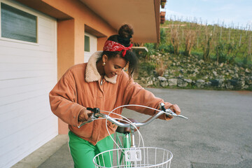 Outdoor fashion portrait of pretty african woman walking with bicycle 