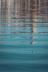 Reflections of buildings shimmer in calm waters on a sunny afternoon near the marina